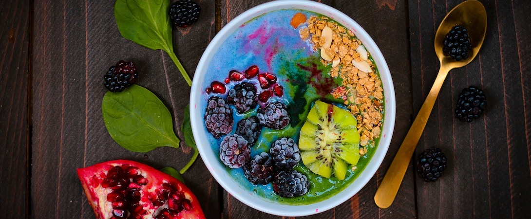 a colourful breakfast bowl of a smoothie and berries