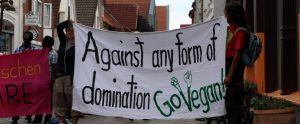 animal activists holding up a sign that says "Against any form of domination Go Vegan!"
