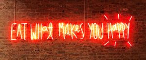 a red neon sign that says "Eat What Makes You Happy"