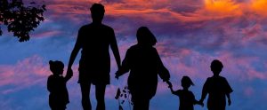 the silhouette of a family with a scenic backdrop of the sky