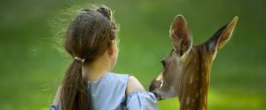 a girl standing next to a deer