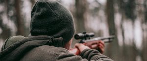 man in the woods with a hunting rifle