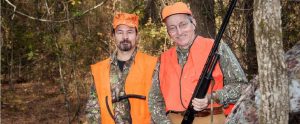 two hunters with high visibility vests and hunting rifles