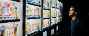 a man deciding what to buy in front of a row of vending machines