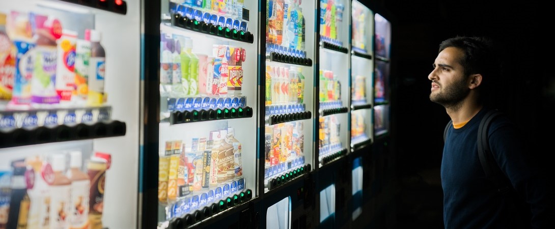 a man deciding what to buy in front of a row of vending machines