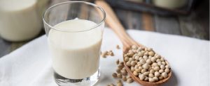 soy milk next to a wooden ladle of soy beans