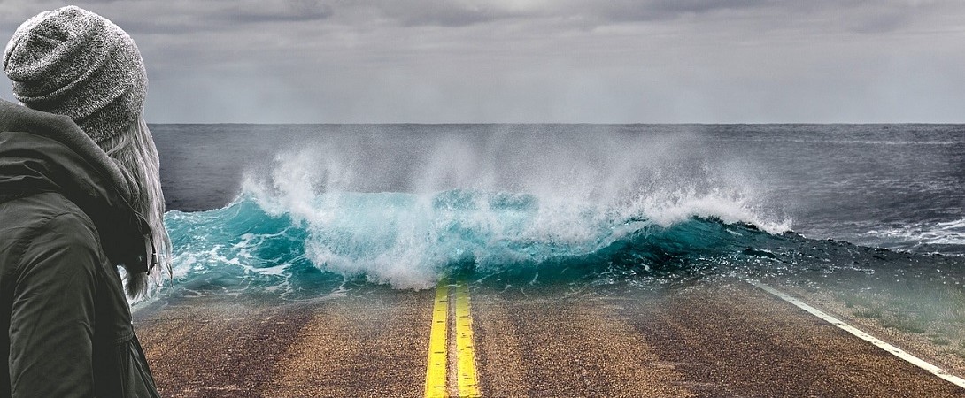 a woman standing looking at waves on the road