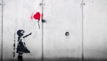 a graffiti picture of a girl with a red balloon escaping her hand
