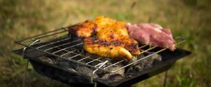 pieces of cooked and uncooked meat on unlit barbecue
