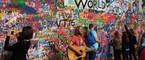 people hanging around a wall with hipster graffiti and a man playing a guitar