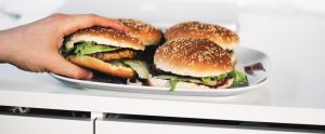 hand grabbing a vegan burger off a plate