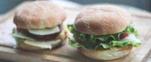 two burgers on a wooden cutting board