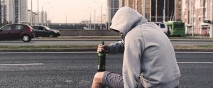 an alcoholic homeless man drinking beer on the streets