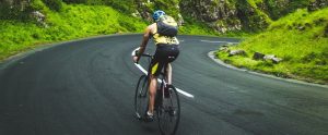 man cycling on a downhill road
