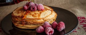 pancakes with maple syrup and frozen raspberries on a plate