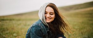 hooded woman smiling with her hand blowing in the wind