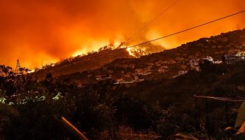 a forest fire near a city built on mountains