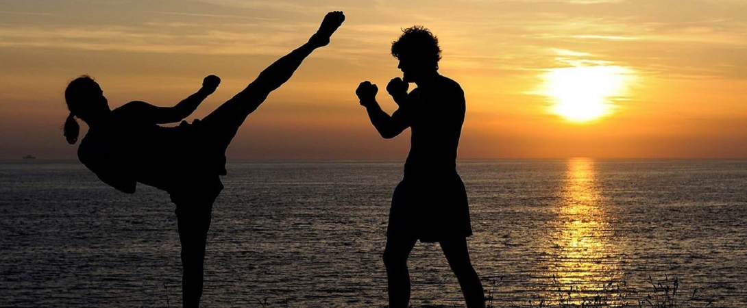 silhouette of a man and woman kick boxing