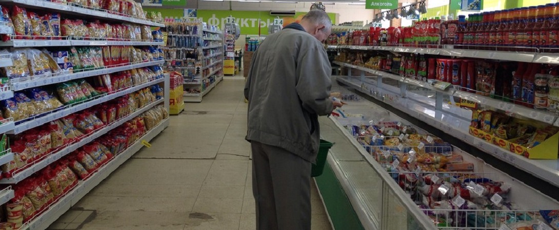 elderly man looking at products in a supermarket aisle
