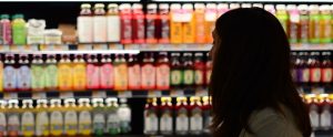 woman in a shopping aisle of different juices