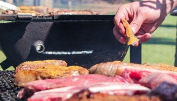 man putting sauce on a meat barbecue