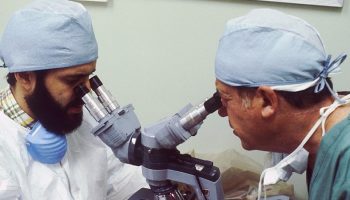 two scientists looking into a two person microscope