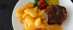 beef, chips, pickles and ketchup on a plate