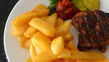 beef, chips, pickles and ketchup on a plate