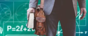professor holding a large textbook and leather bag with a chalkboard background