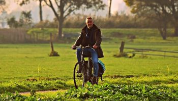 man cycling with a dog trailing behind him