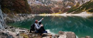 a man and a woman sitting near a large lake