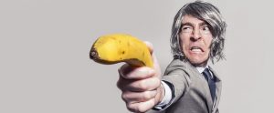 a man in a suit holding a banana in the form of a gun