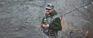 a smiling man fishing in a river