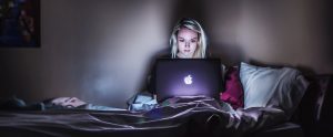 a woman in her bed at night using her MacBook