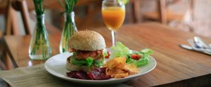 a plate with a burger, fries and vegetables on it next to a glass of orange juice