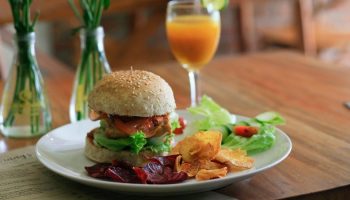 a plate with a burger, fries and vegetables on it next to a glass of orange juice