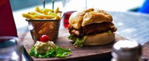 fastfood burger and fries on a wooden cutting board