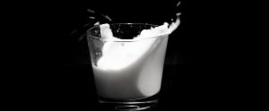 a glass of milk splashing in a glass with a black background