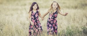 two child sisters running through a field