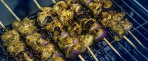 meat on wooden skewers being cooked on barbecue