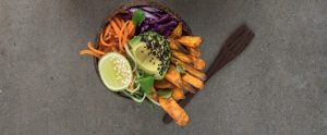 bowl of avocado, chips and vegetables next to a fork