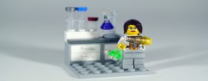 lego researcher pouring green chemicals into a beaker