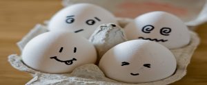 four eggs with faces drawn on them in a carton