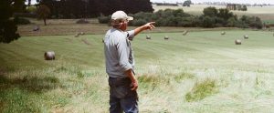 a farmer pointing at a farm