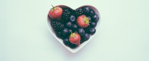 blueberries and strawberries in a white heart shaped bowl