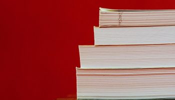 four books piled on top of each other with a red background