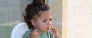 a upset child hesitantly eating vegetables