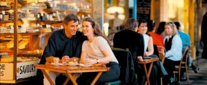 people sitting outside a cafe enjoying coffee and desserts