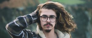a hipster with his long brown hair blowing in the wind