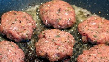 minced meat being cooked with olive oil in a frying pan